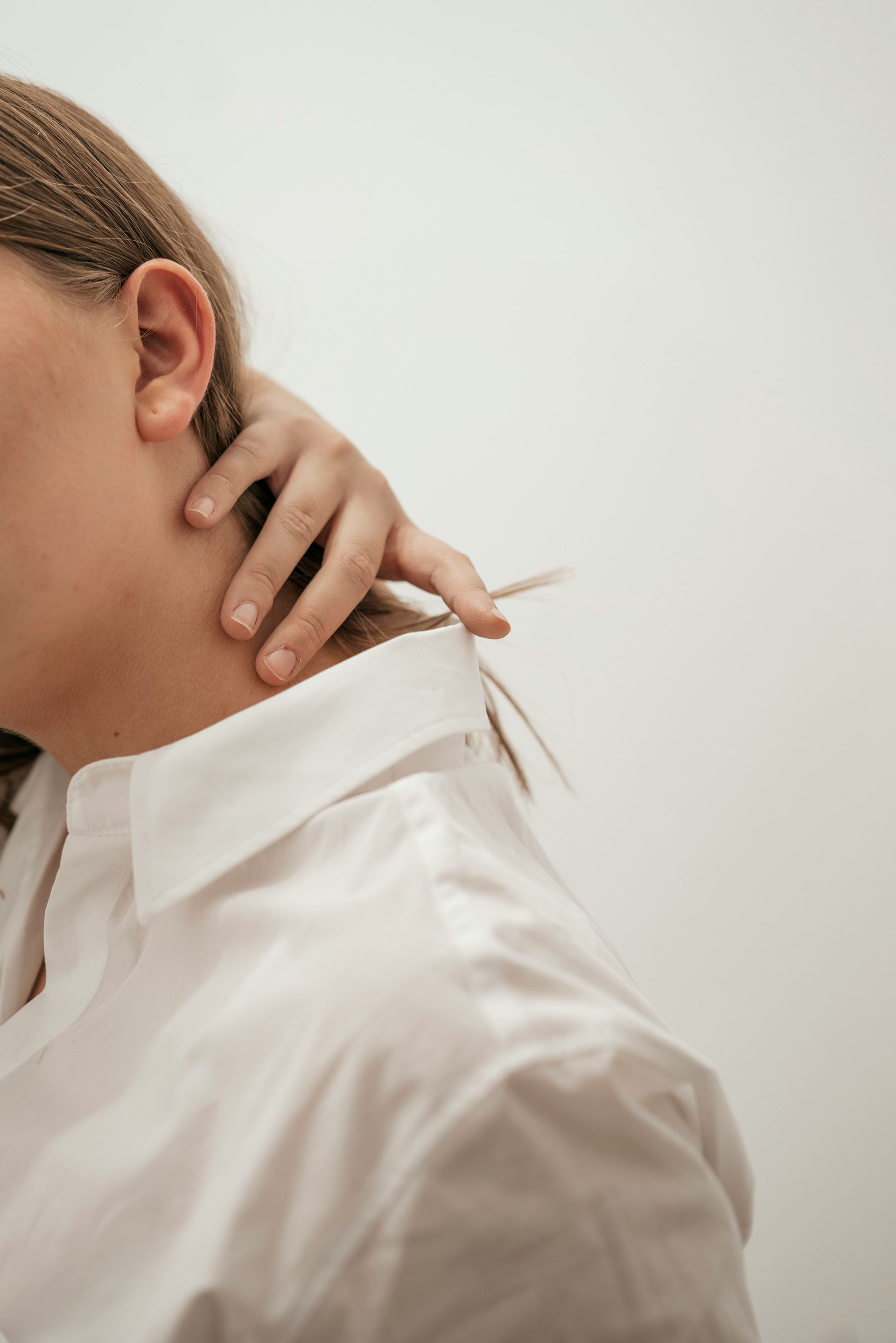 person holding their neck with their fingers